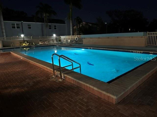 pool at twilight with a community pool and fence