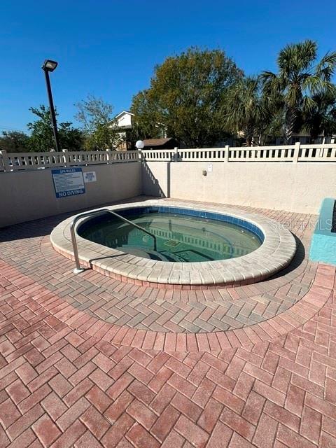 view of swimming pool featuring a community hot tub and fence