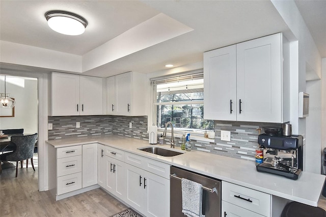 kitchen with light wood-style flooring, dishwasher, light countertops, and a sink