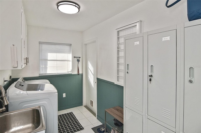 laundry area featuring a sink, a wainscoted wall, light tile patterned floors, cabinet space, and separate washer and dryer