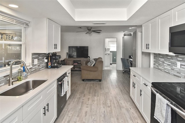 kitchen featuring light wood finished floors, visible vents, a tray ceiling, appliances with stainless steel finishes, and a sink