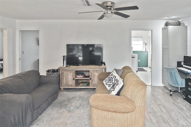 living room with light wood-type flooring, visible vents, and a ceiling fan