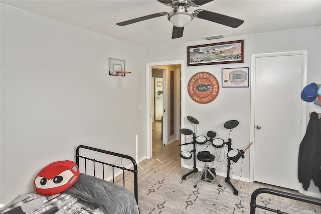 bedroom with a ceiling fan, light wood-style floors, visible vents, and baseboards