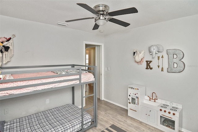 bedroom with light wood-style flooring, visible vents, baseboards, and ceiling fan