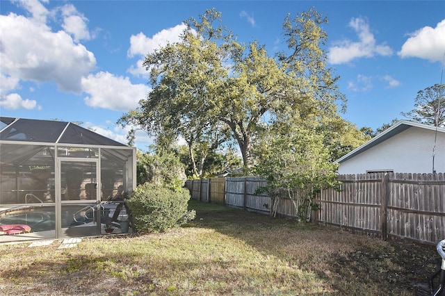 view of yard with glass enclosure, a fenced backyard, and a fenced in pool