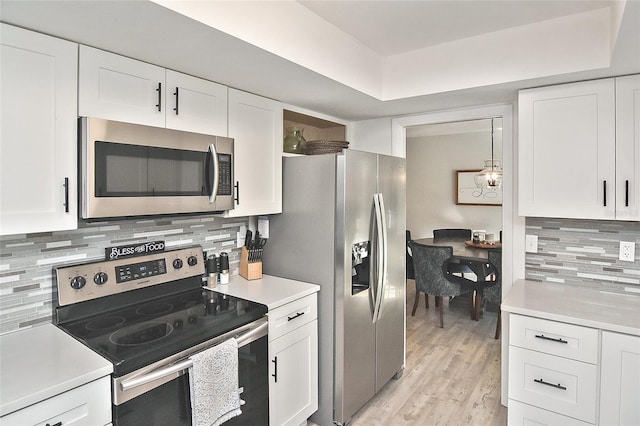 kitchen featuring white cabinetry, backsplash, appliances with stainless steel finishes, and light countertops