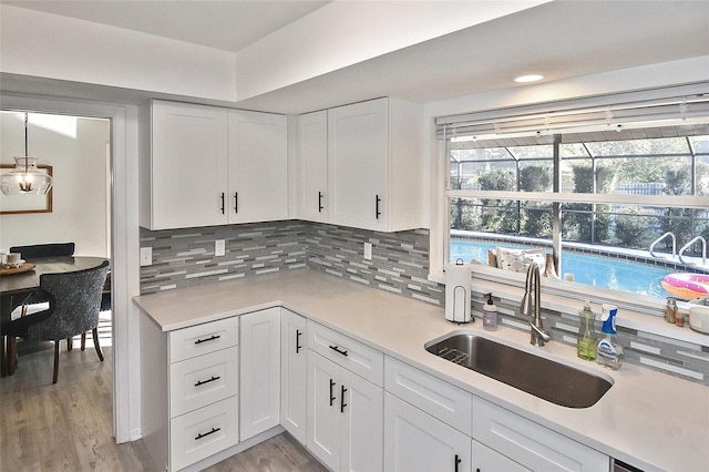 kitchen with a sink, light countertops, white cabinets, light wood-type flooring, and a wealth of natural light