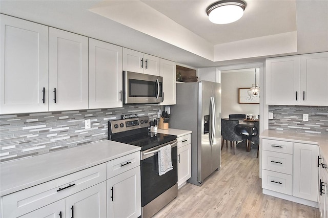 kitchen featuring appliances with stainless steel finishes, white cabinetry, and a raised ceiling