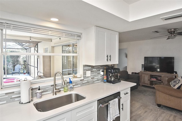 kitchen featuring visible vents, a sink, open floor plan, stainless steel dishwasher, and tasteful backsplash