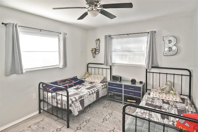 bedroom with light wood-type flooring, multiple windows, baseboards, and ceiling fan