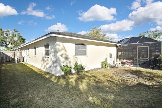 view of side of home with fence, a lanai, central air condition unit, stucco siding, and a yard