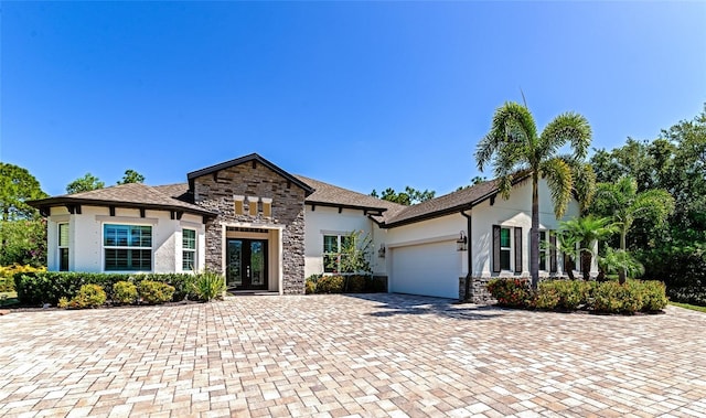 view of front of house featuring stone siding, stucco siding, decorative driveway, and a garage