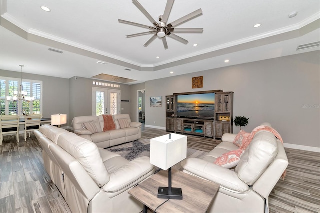 living area with a tray ceiling, crown molding, baseboards, and visible vents