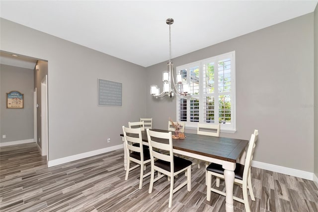 dining area featuring a notable chandelier, baseboards, and wood finished floors