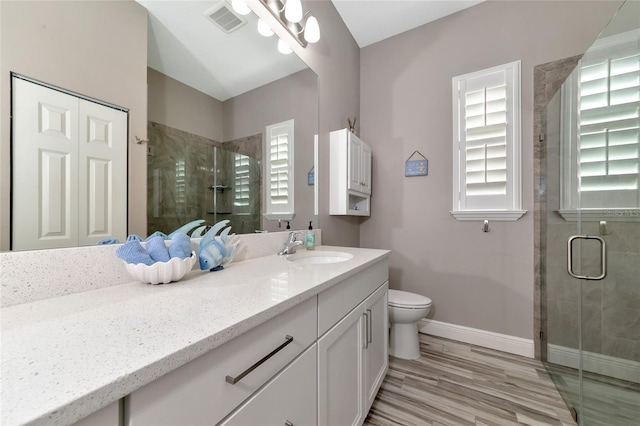 bathroom featuring vanity, baseboards, visible vents, a stall shower, and toilet