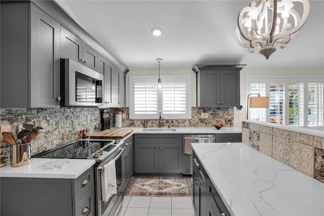 kitchen with a sink, stainless steel appliances, tasteful backsplash, and gray cabinets