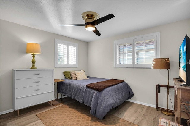 bedroom with a ceiling fan, wood finished floors, and baseboards