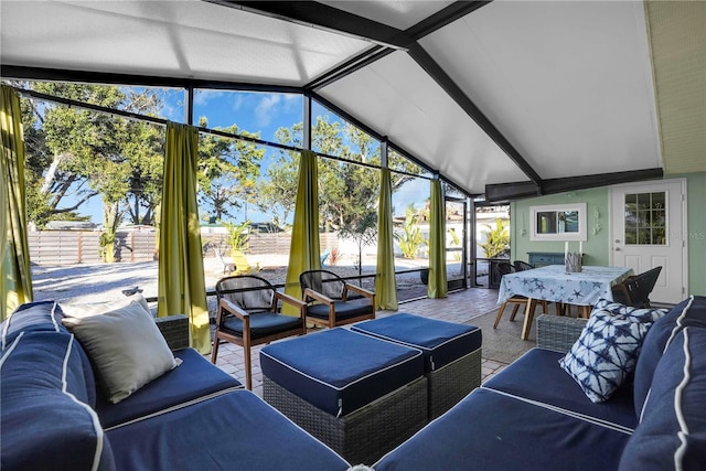 sunroom featuring a healthy amount of sunlight and vaulted ceiling with beams