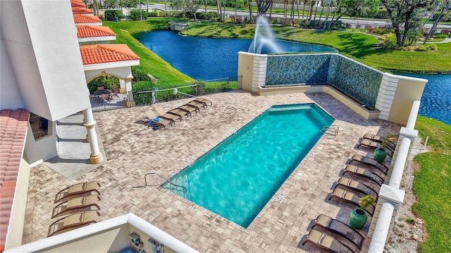 view of pool with fence, a patio, and a water view