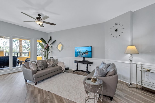 living room featuring ceiling fan, wood finished floors, and wainscoting