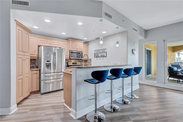 kitchen featuring a kitchen bar, light stone countertops, visible vents, and stainless steel appliances