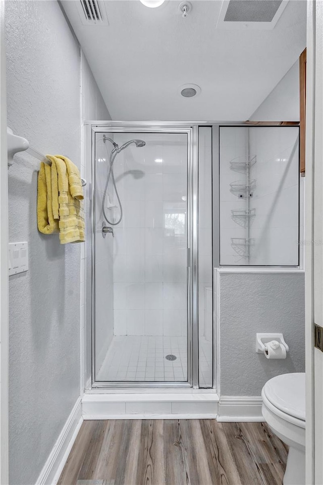 full bath with wood finished floors, visible vents, a shower stall, toilet, and a textured wall