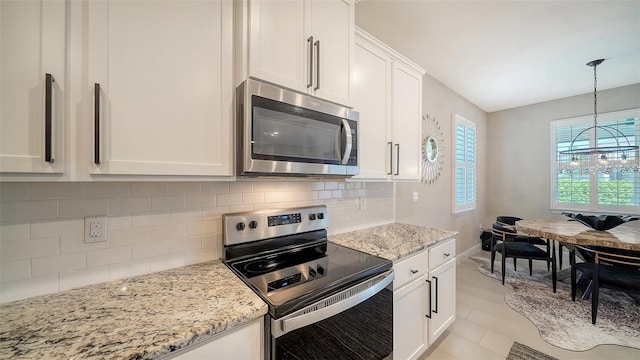 kitchen with tasteful backsplash, white cabinets, appliances with stainless steel finishes, and light stone counters