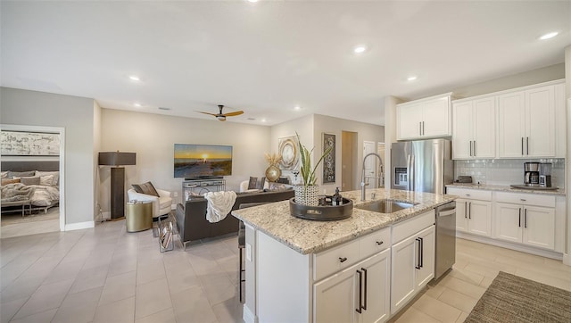 kitchen with a sink, decorative backsplash, appliances with stainless steel finishes, and open floor plan