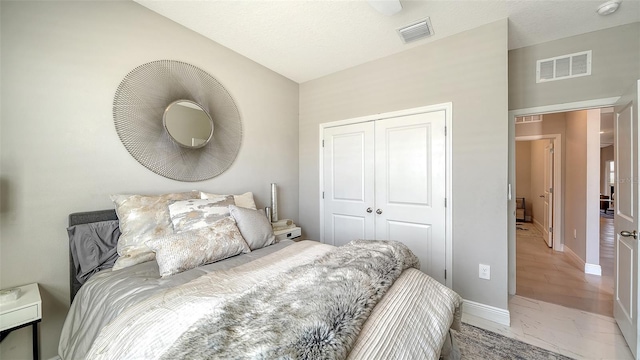 bedroom with visible vents, baseboards, marble finish floor, and a closet