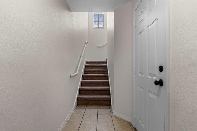 stairs featuring tile patterned flooring, a textured wall, and baseboards