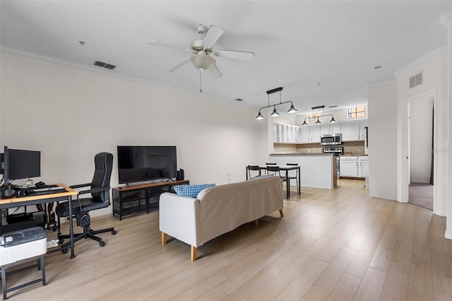 living room featuring crown molding, light wood-style floors, visible vents, and ceiling fan