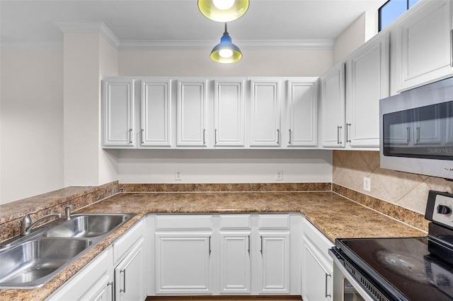 kitchen with dark countertops, a sink, appliances with stainless steel finishes, white cabinetry, and crown molding