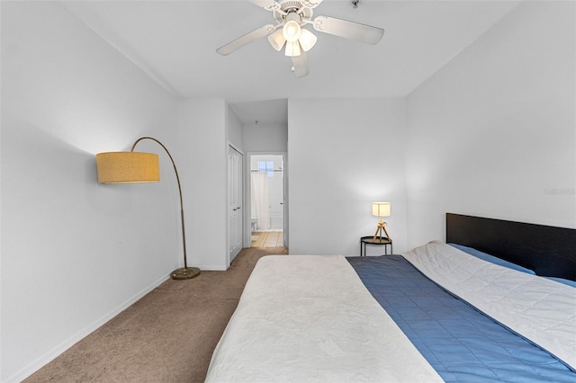 carpeted bedroom featuring ensuite bath, baseboards, and a ceiling fan