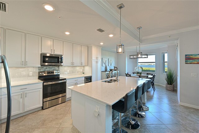 kitchen featuring visible vents, a sink, tasteful backsplash, appliances with stainless steel finishes, and crown molding