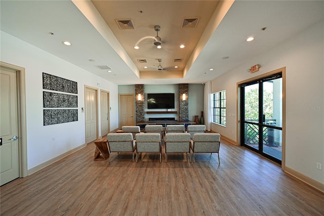 living room with a raised ceiling, recessed lighting, wood finished floors, and visible vents