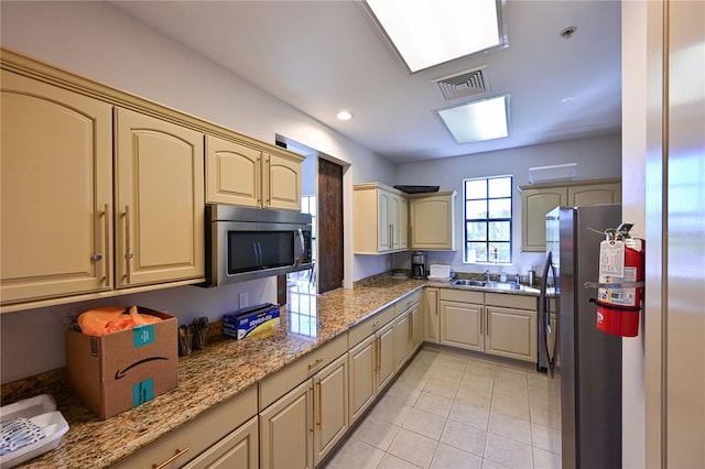 kitchen with light stone countertops, visible vents, light tile patterned flooring, a sink, and stainless steel appliances