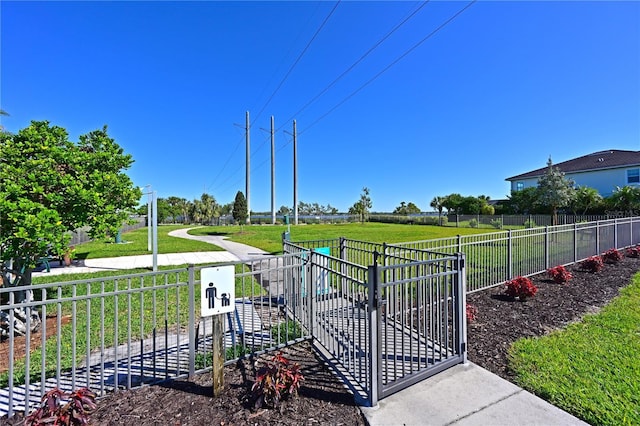 view of property's community with a gate, a lawn, and fence