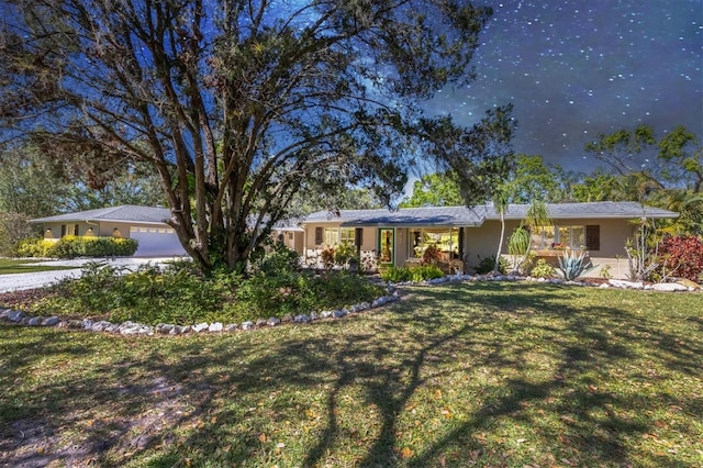 ranch-style house with a garage, stucco siding, concrete driveway, and a front lawn