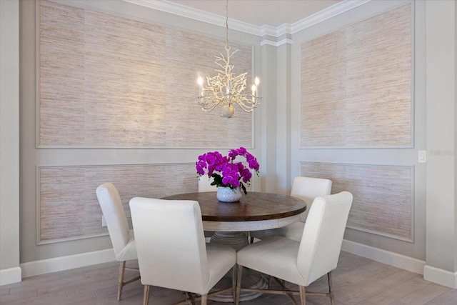 dining room featuring a notable chandelier, ornamental molding, baseboards, and wood finished floors