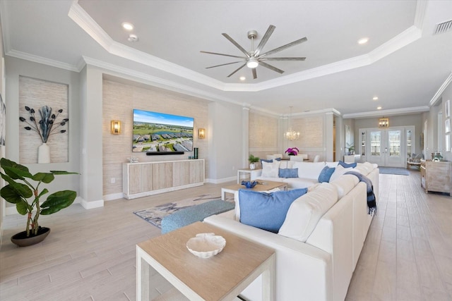 living area featuring light wood finished floors, french doors, a tray ceiling, and ornamental molding