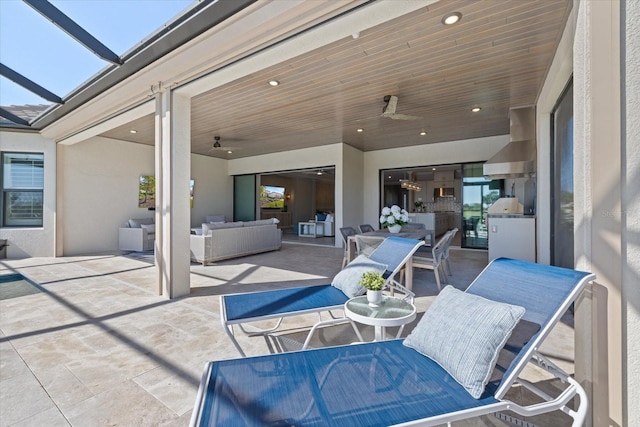 view of patio featuring a lanai, exterior kitchen, outdoor lounge area, outdoor dining area, and a ceiling fan