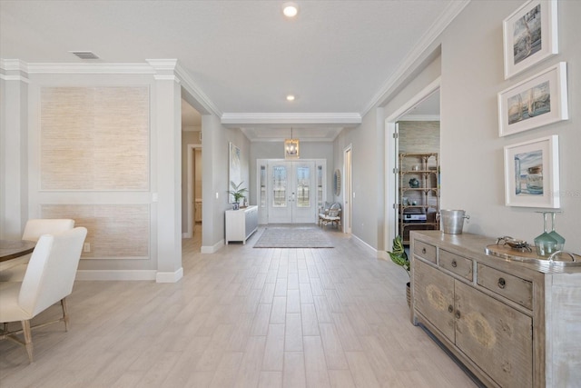 entrance foyer featuring baseboards, visible vents, light wood-style flooring, ornamental molding, and french doors