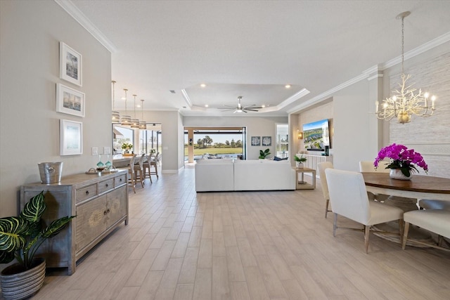 living area featuring light wood finished floors, plenty of natural light, a raised ceiling, and ornamental molding