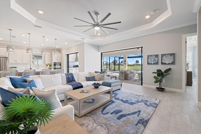 living area featuring a ceiling fan, visible vents, crown molding, light wood-style floors, and a raised ceiling