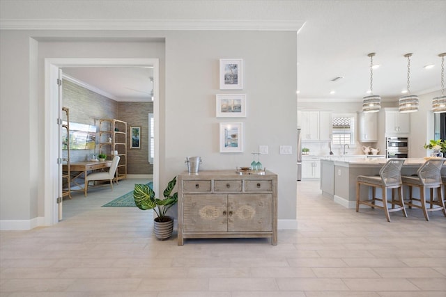 interior space with light wood finished floors, baseboards, and ornamental molding