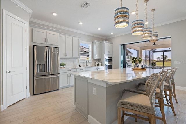 kitchen with visible vents, backsplash, a center island, a kitchen bar, and stainless steel appliances