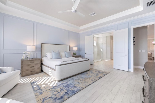 bedroom featuring a decorative wall, light wood-style flooring, and visible vents