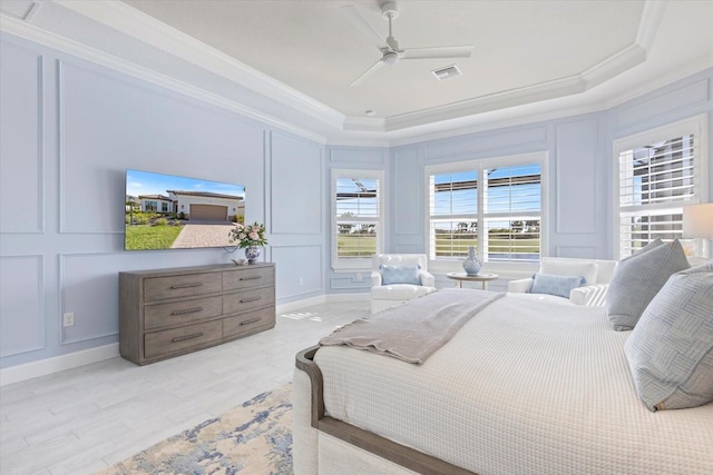 bedroom featuring crown molding, a decorative wall, visible vents, and a tray ceiling