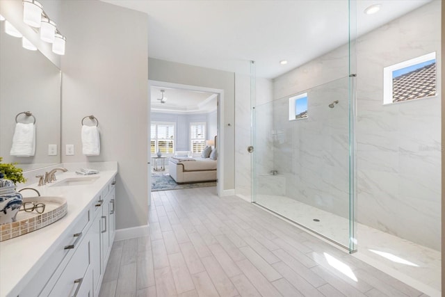 bathroom with a marble finish shower, baseboards, wood finished floors, ensuite bath, and a sink