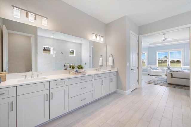 full bath featuring a sink, baseboards, double vanity, and a walk in shower